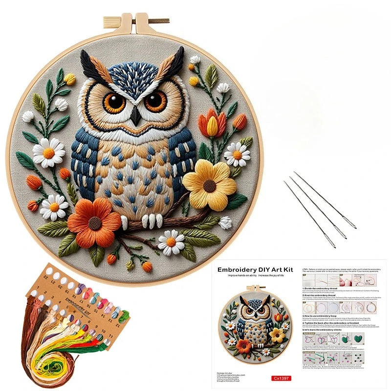 A DIY embroidery kit featuring an owl and floral design on a canvas with thread and tools.