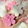 Hand holding pink and white silicone flower molds for soap, candle, and craft making
