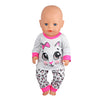 A baby doll wearing a white long-sleeved shirt with a pink collar and a cat face design, paired with patterned leggings.
