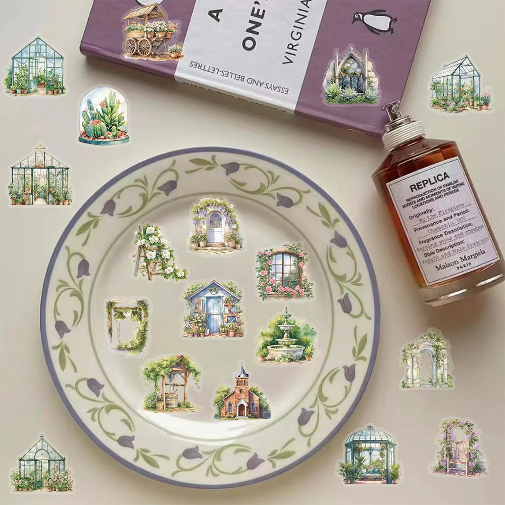 A plate decorated with floral patterns and illustrations of glasshouses, alongside a box of essays and letters.