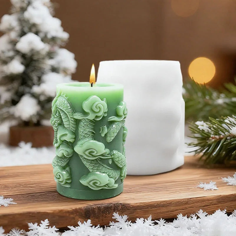 A green silicone candle mold shaped like dragons and clouds sits on a wooden surface next to a white candle.