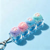 A set of light-up silicone paw print keycaps arranged in a row on a light blue background with a silver keychain attached.
