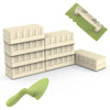 A set of sand and snow building play components including molds, bricks, and a shovel on a green mat.