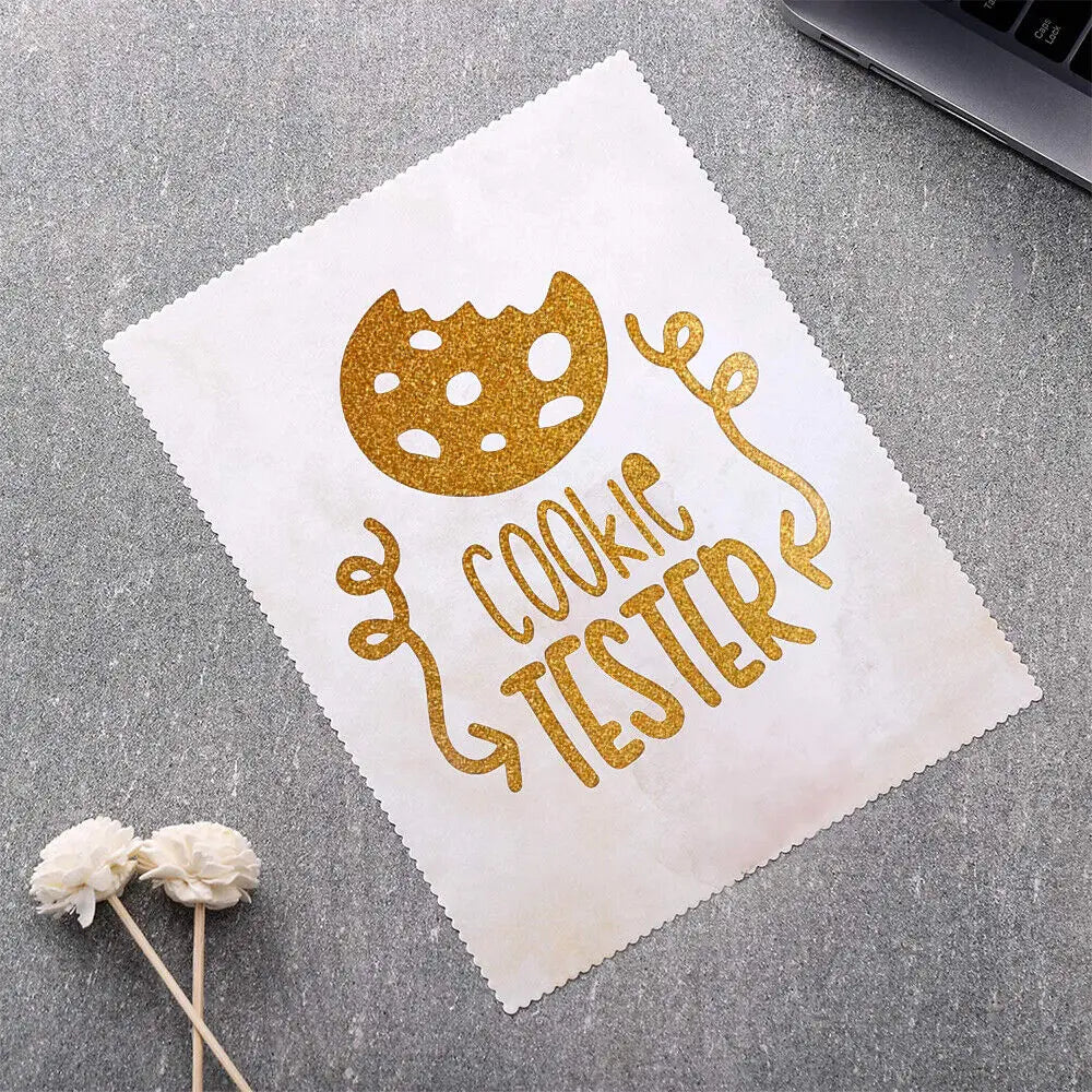 A sheet of parchment paper with gold glitter text reading COOKIE TESTER is placed on a gray surface next to some cotton balls