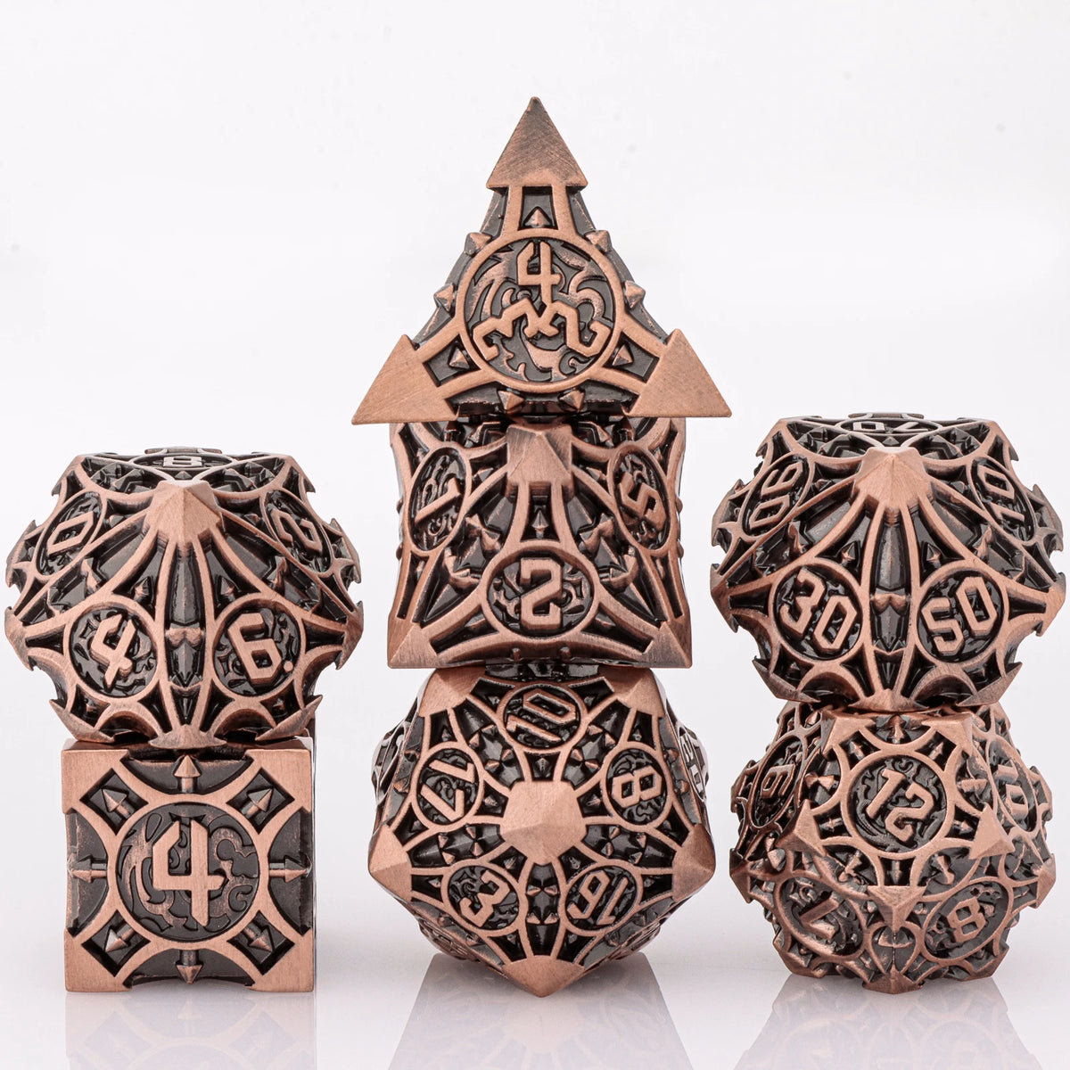 A set of seven intricately detailed metal dice featuring skull and dragon designs in a bronze color.