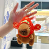 An adorable orange capybara plush charm with gold-colored hoop and jump ring attached to a finger.
