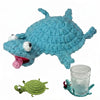 A handmade blue crochet lizard figurine resting next to a small green crochet lizard and a glass coaster.