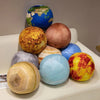 A collection of spherical plush toys representing planets, including Earth and various other celestial bodies.