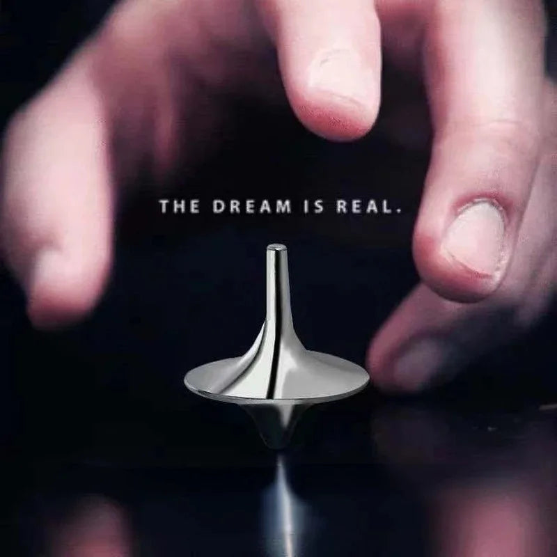A hand holds a polished metal fidget spinner against a dark background with the text The dream is real.