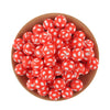 A pile of bright red silicone beads with white polka dots in a wooden bowl.
