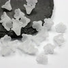 Clear frosted acrylic flower beads scattered on a dark stone surface