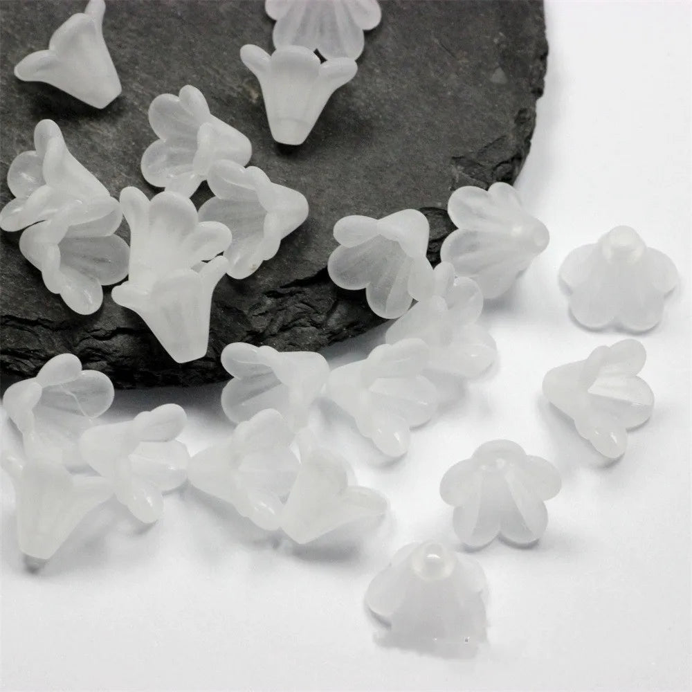 Clear frosted acrylic flower beads scattered on a dark stone surface