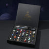 A black gift box containing a collection of natural crystal and mineral specimens, including various stones and a magnifying 