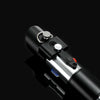 A close-up view of a black lightsaber hilt with silver accents and a red switch, set against a dark background.