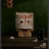 A plush doll resembling a face is displayed on a wooden surface against a dark green background.