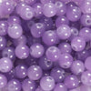 A close-up view of small, round purple glass beads for DIY jewelry making.