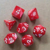 A collection of ten red acrylic polyhedral dice showing various numbers and shapes on a brown surface.