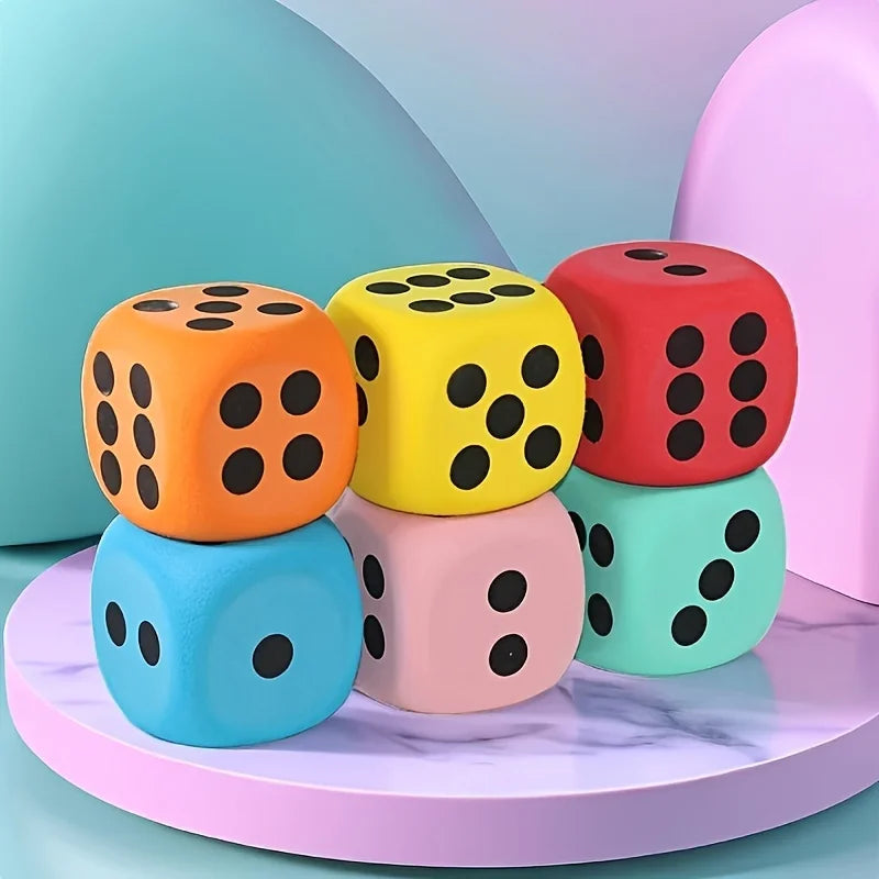 A stack of colorful jumbo soft foam dice in orange, yellow, red, blue, and pink on a purple marble surface.