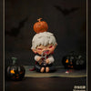 A collectible figure of a small monster with orange skin and white hair, sitting in front of a black pumpkin.