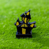 A black cartoon pumpkin bear figurine with yellow accents resting on green grass.