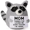 A gray handmade crochet animal plush doll with black markings and a sign that reads MOM THANKS FOR LOVING ME EVEN THOUGH I'M 