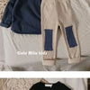 A beige long sleeve cotton tee and matching pants with blue accents laid on a white surface.