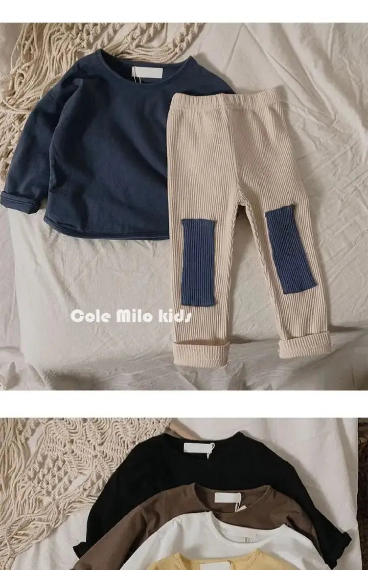 A beige long sleeve cotton tee and matching pants with blue accents laid on a white surface.