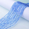 A close-up of blue iridescent faceted glass crystal beads strung together, draped over a white surface.