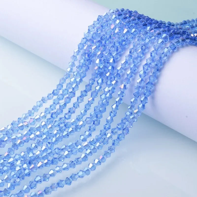 A close-up of blue iridescent faceted glass crystal beads strung together, draped over a white surface.