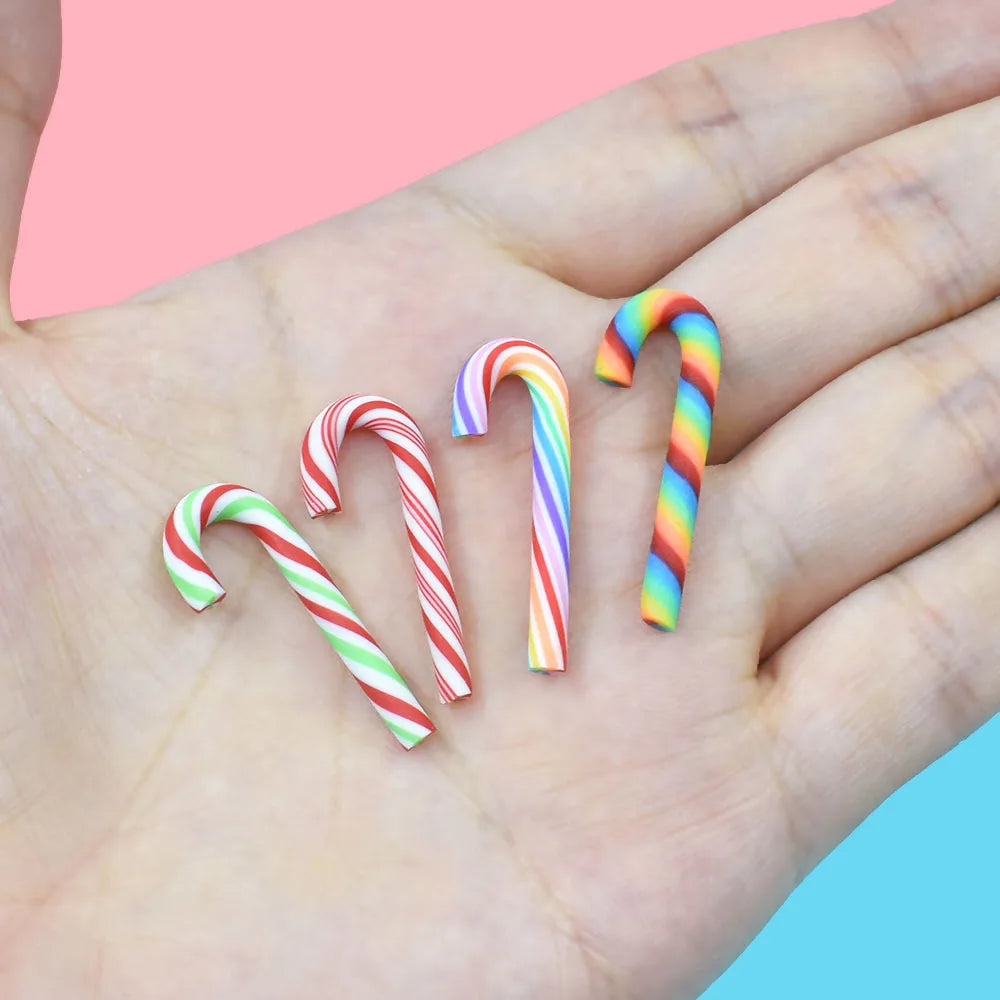 A hand holds five colorful striped candy cane polymer clay charms on a light background.