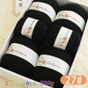 A box containing six balls of black wool yarn for knitting, labeled as 100% Merino Wool Yarn.