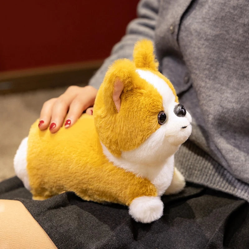A fluffy orange and white Corgi plush toy being held by a person.