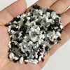 A handful of natural tumbled stone chips in black, white, and gray shades resting on a hand.