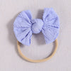 A light purple fabric bow headband with a soft elastic band resting on a white background.