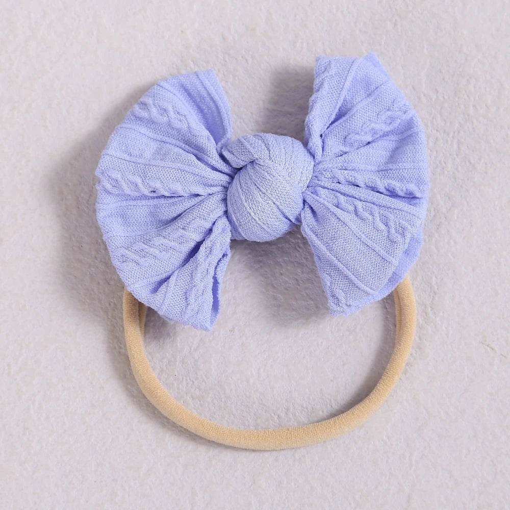 A light purple fabric bow headband with a soft elastic band resting on a white background.