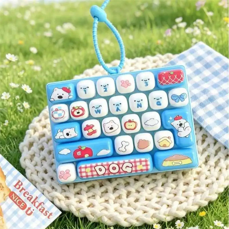 A blue cartoon animal keyboard keycap set with a dog theme resting on a knitted surface in a grassy outdoor setting.