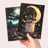 A hand holds a dark card featuring a glowing moon and castle silhouette with stars and sparkles.