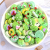 A bowl filled with assorted green and yellow candy resin flatbacks for DIY crafts and jewelry making