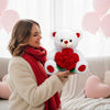 A woman in a beige coat and red scarf holds an adorable white plush bear with a red rose.