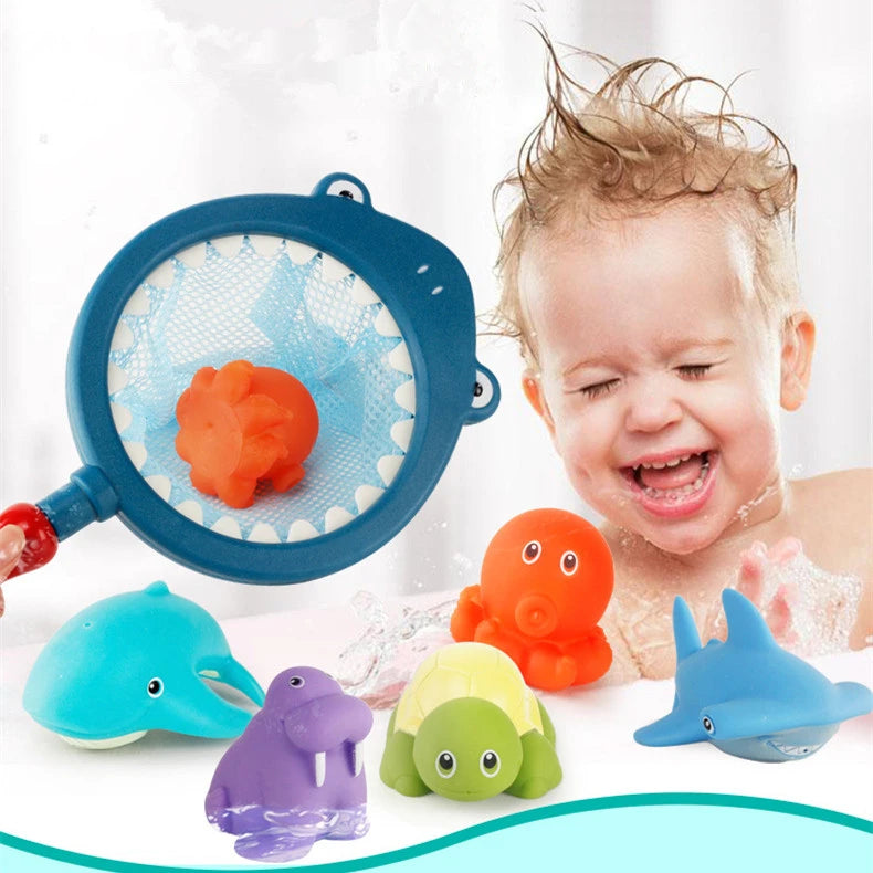 A baby is playing with an orange water-squirting turtle bath toy and a blue fishing net in a bathtub.