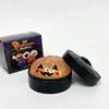 A black tin of Halloween-themed squishy stress relief toy with a glowing orange face design.