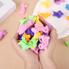A hand holds a pile of colorful animal and dinosaur sensory stress bracelets for kids on a white surface.
