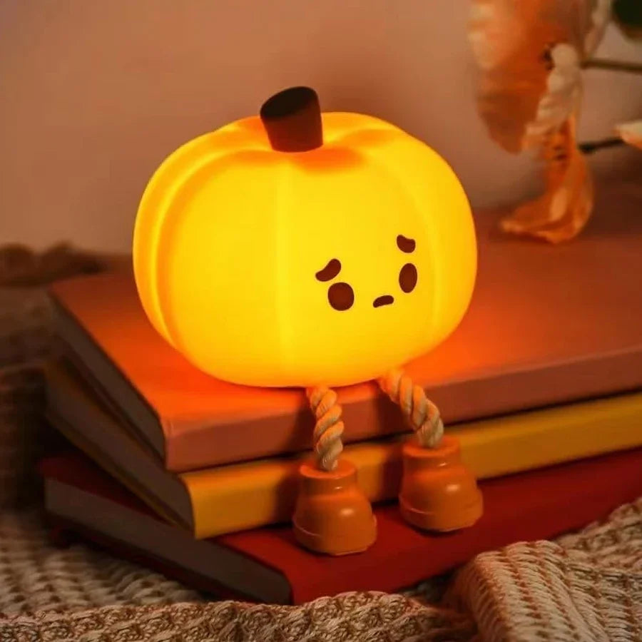A glowing orange pumpkin LED night light rests on a stack of books.