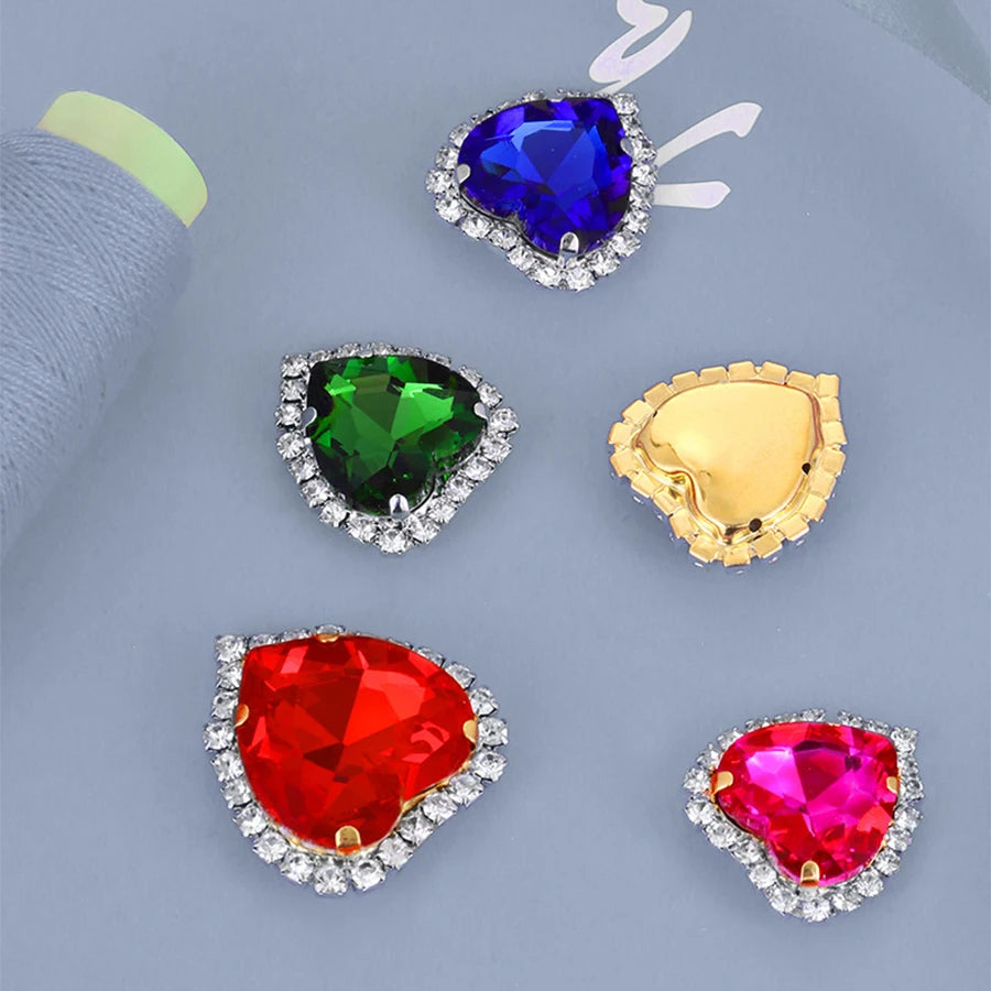A collection of heart-shaped flatback sew-on rhinestones in various colors including blue, green, gold, and red, set against 