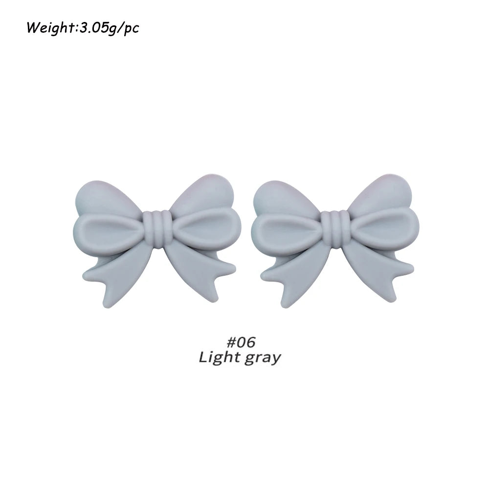 Two light gray silicone bow tie beads for jewelry making and craft projects