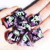 A hand holds a set of purple and black resin polyhedral dice with white skull and floral designs.