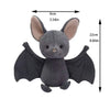 A grey bat plush toy with large ears and black wings is shown against a white background.