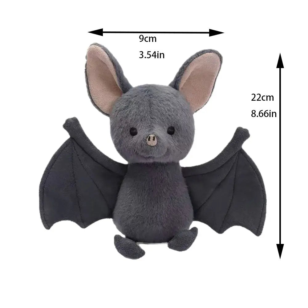 A grey bat plush toy with large ears and black wings is shown against a white background.