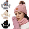 A woman models a pink knit winter hat, scarf, and gloves set with faux fur pom, showing the full product collection.