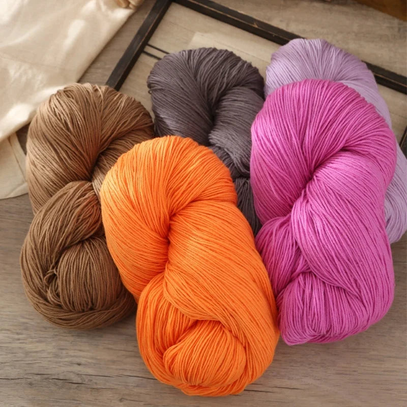 A collection of skeins of premium alpaca blend yarn in various shades including beige, gray, orange, and pink.